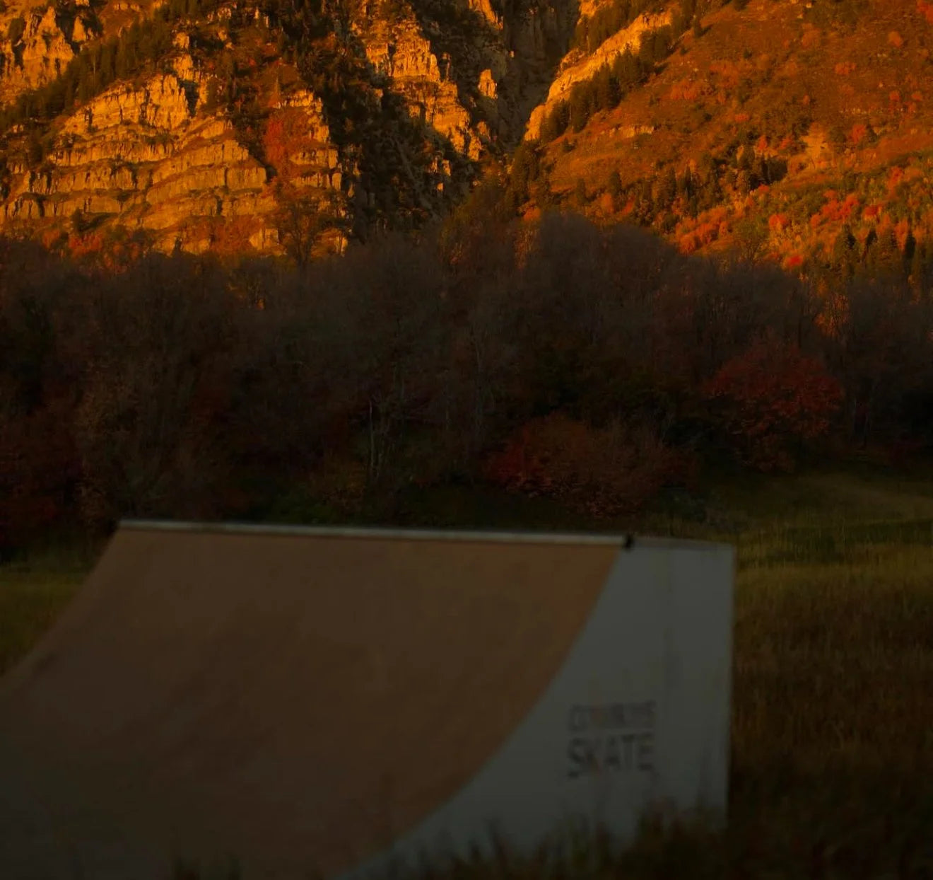 A skater dropping in on the half-pipe at dusk